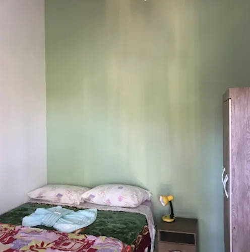Quarto de casal com edredom xadrez azul e janela ampla com vista verde