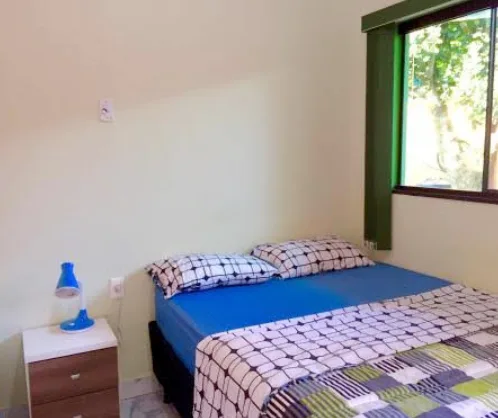 Quarto de casal com janela voltada para árvore e luz natural