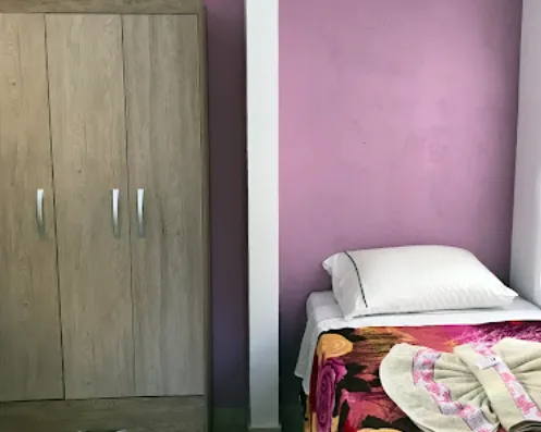Quarto de solteiro com parede lilás e guarda-roupa de madeira clara